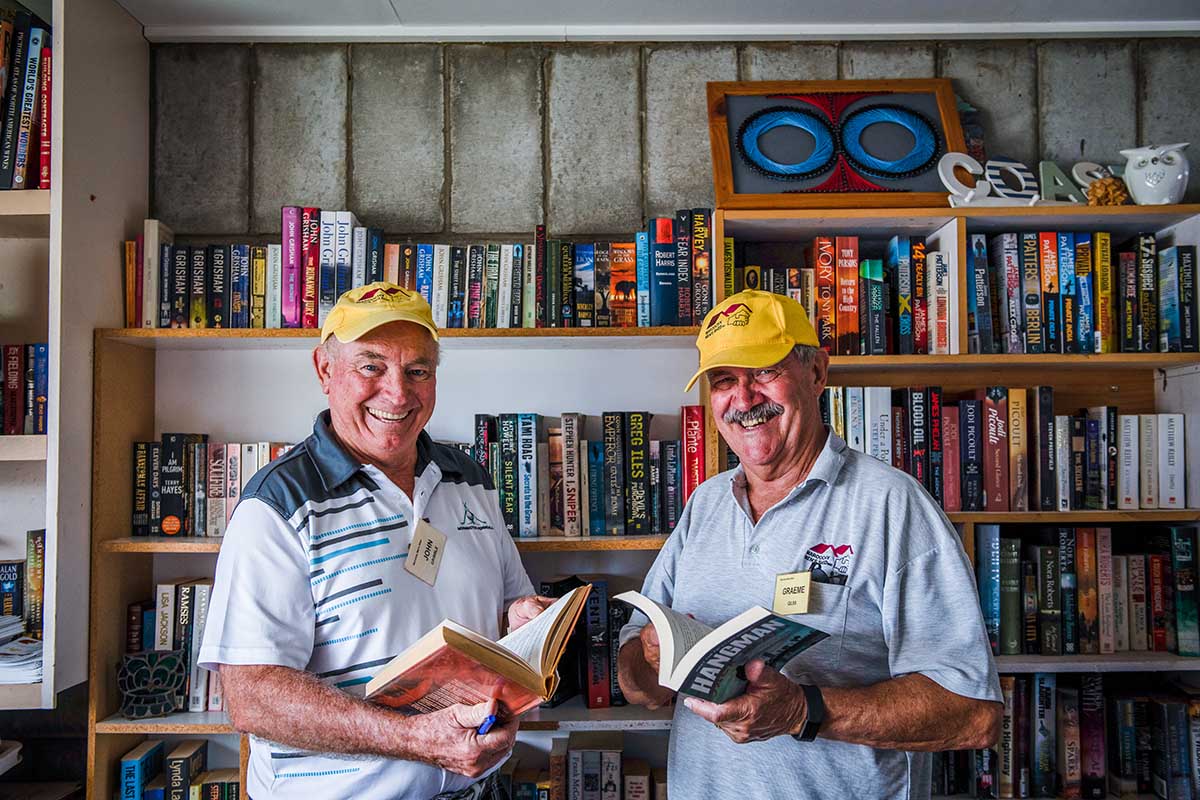 Two men holding books smiling to camera