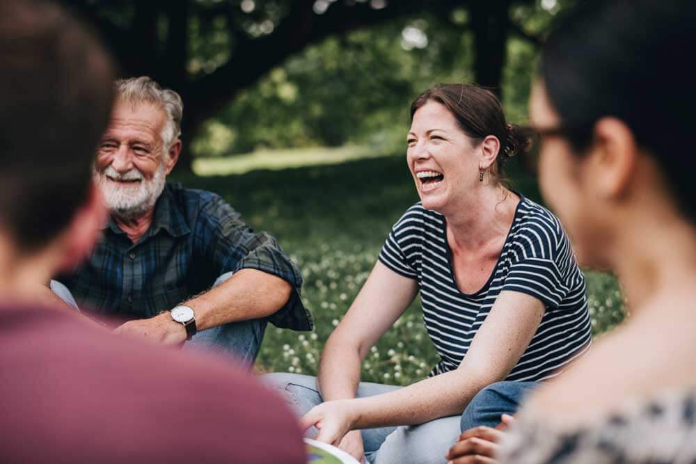 A group of friends sitting in a park laughing