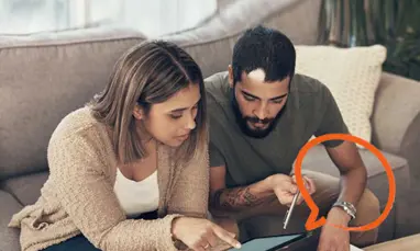 Couple looking at device on a coffee table