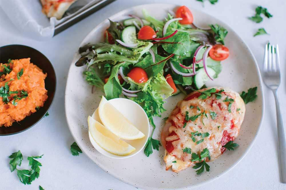 A plate of chicken parmigiana  with a green side salad