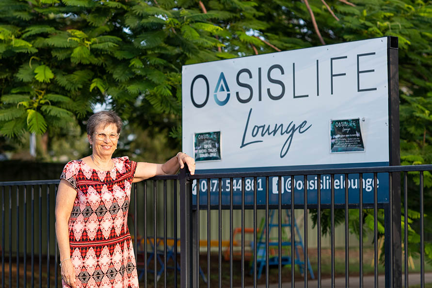 Woman standing in front of Oasis Life Lounge sign