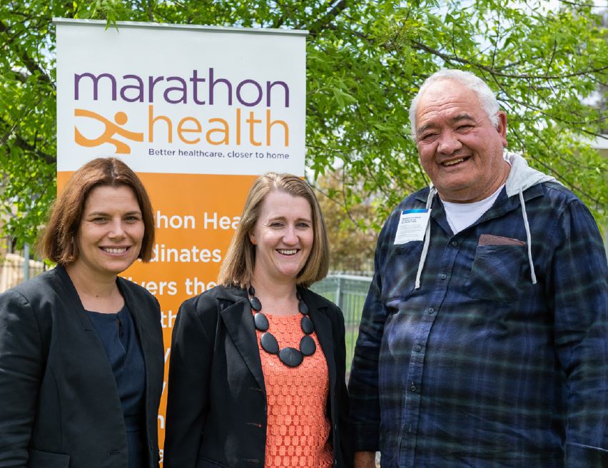 Three people standing in from of Marathon Health banner