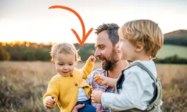 Man in field holding kids
