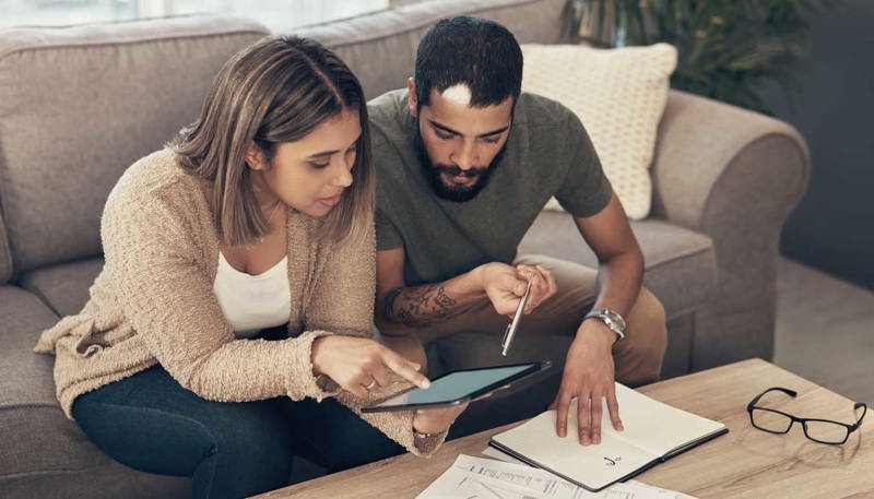 Young Couple Using A Laptop While Going Through Paperwork At Home (1)