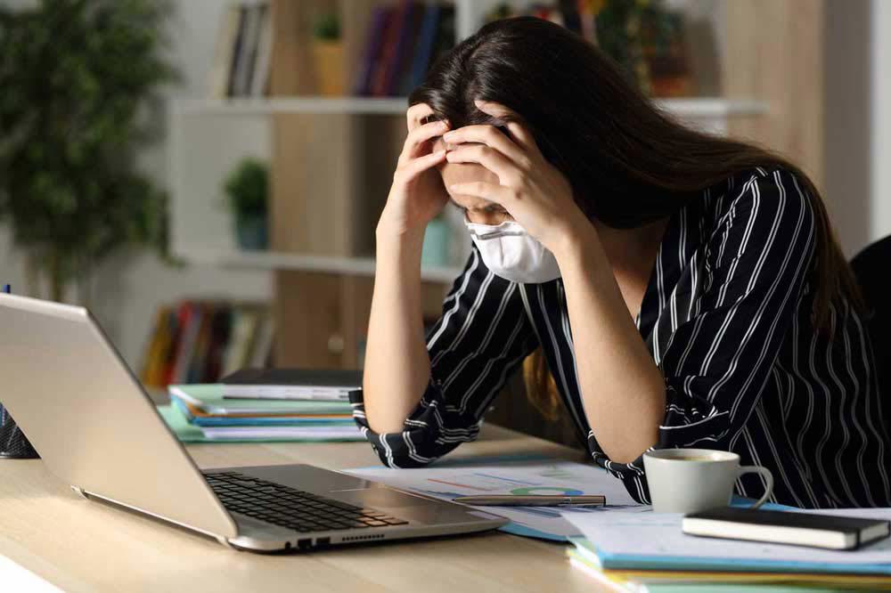 Woman at home office desk looking exhausted