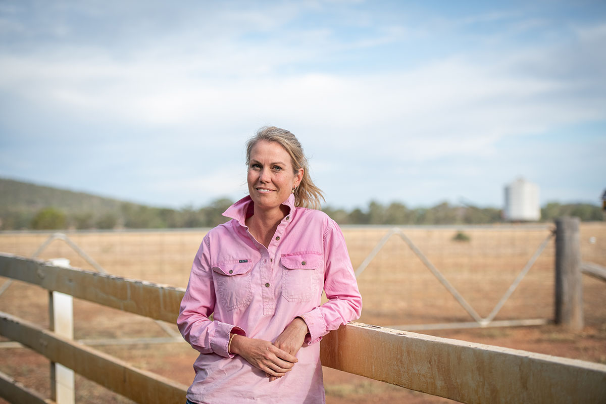 female farmer leaning against fence